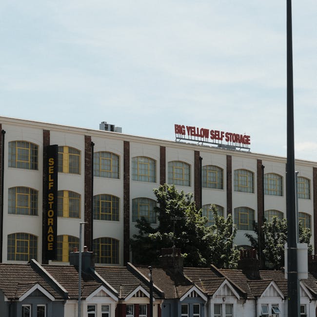 Photograph of a multi-storey building with a sign that reads 'BIG YELLOW SELF STORAGE' on the roof and a vertical sign on the side that says 'SELF STORAGE' in yellow letters on a black background. The