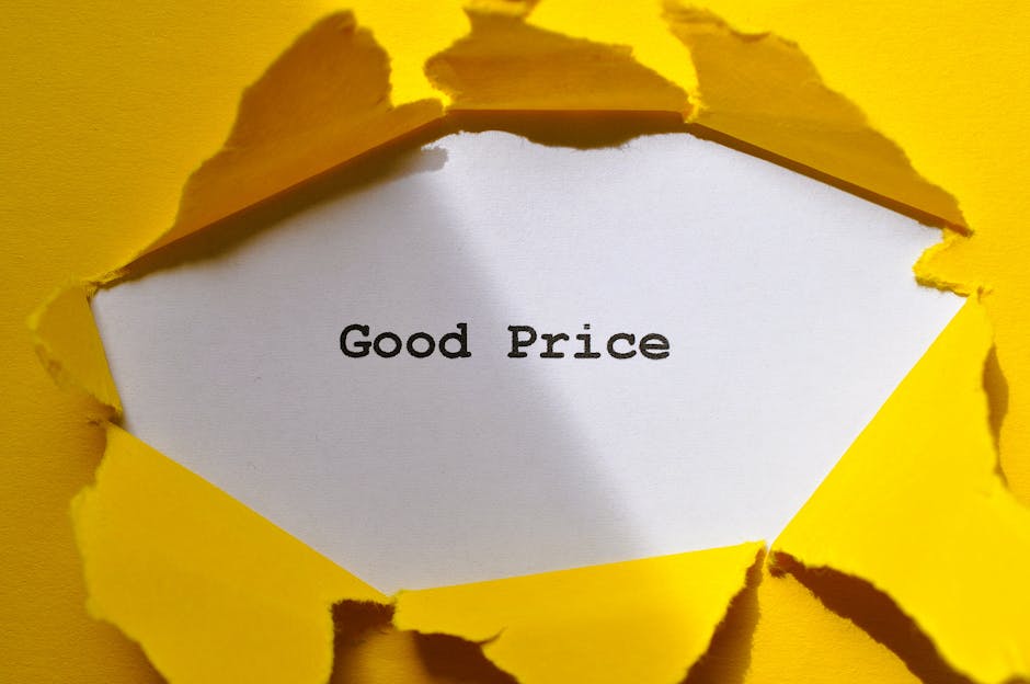 A close-up of a yellow paper surface with a torn section revealing a white interior sheet that displays the text 'Good Price' in black typewriter-style font. The torn edges of the yellow paper are rough and jagged, suggesting it was deliberately ripped to create a window-like opening. The background inside the torn section is plain white, providing contrast to the yellow outer layer. The image is well-lit, highlighting the texture of the torn paper and the clarity of the message. This visual may be associated with the idea of affordable or transparent pricing in house removals or home relocation services, where clear communication about costs is essential. The scene is minimalistic, focusing solely on the message conveyed through the torn paper effect, suitable for illustrating aspects of moving cost transparency or customer value in the context of furniture transport and packing during a removal process, as offered by Man With a Van Finsbury.